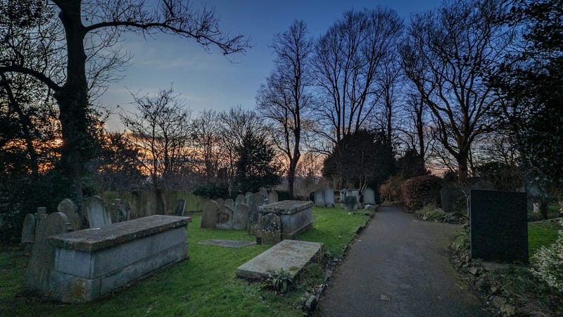 A pathway through a cemetery at dusk