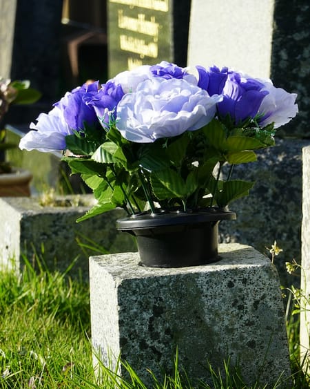 A bouquet of purple and white flowers resting on a granite headstone